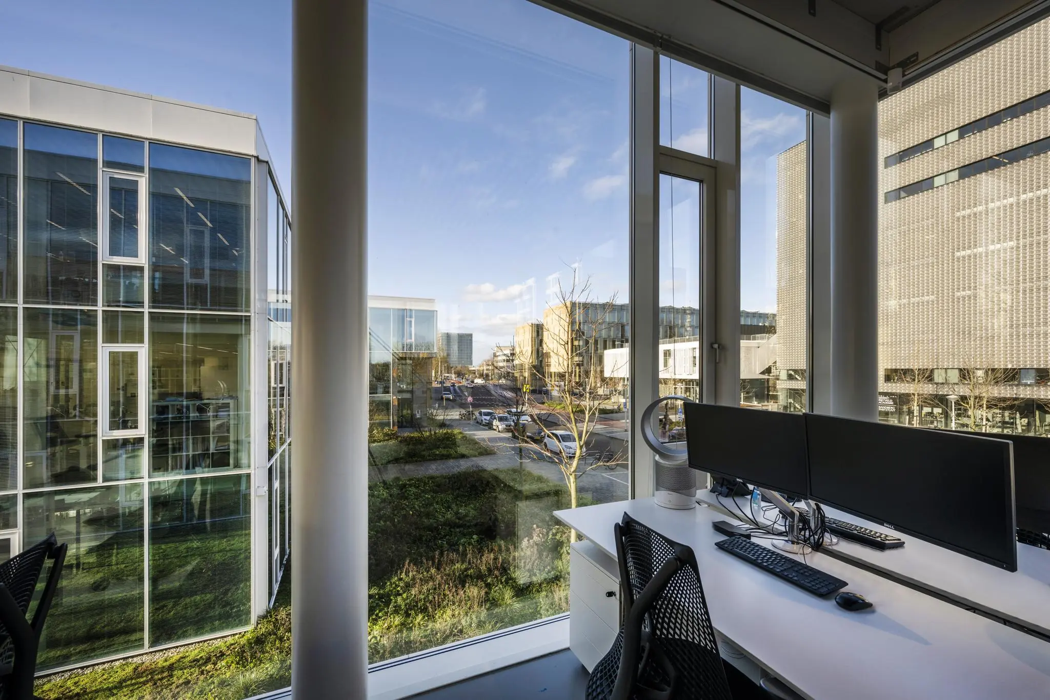 Modern kantoor met werkplek en uitzicht op de Fred. Roeskestraat in een stedelijke omgeving met glazen kantoorgebouwen.